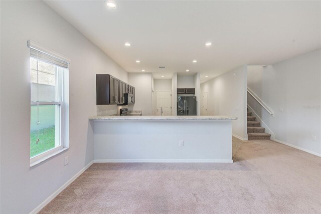 kitchen with black refrigerator with ice dispenser, a wealth of natural light, and baseboards