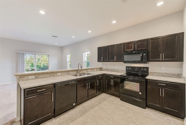 kitchen featuring black appliances, a peninsula, a sink, and recessed lighting