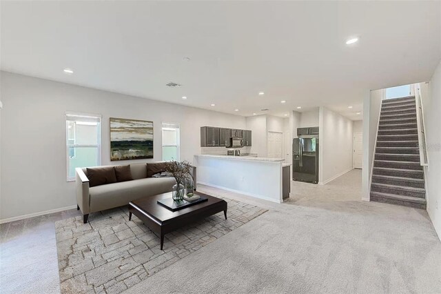 living area with recessed lighting, light carpet, stairway, and baseboards