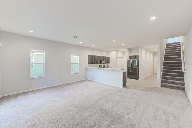 unfurnished living room featuring stairs, recessed lighting, baseboards, and light colored carpet