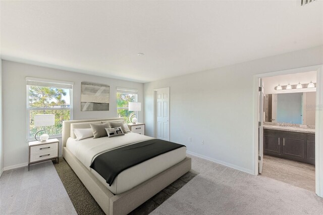 bedroom featuring light carpet, baseboards, and connected bathroom