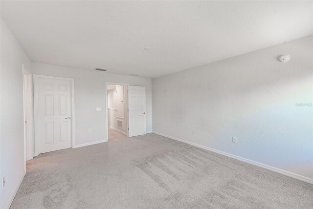 unfurnished bedroom featuring baseboards, visible vents, carpet flooring, and ensuite bathroom