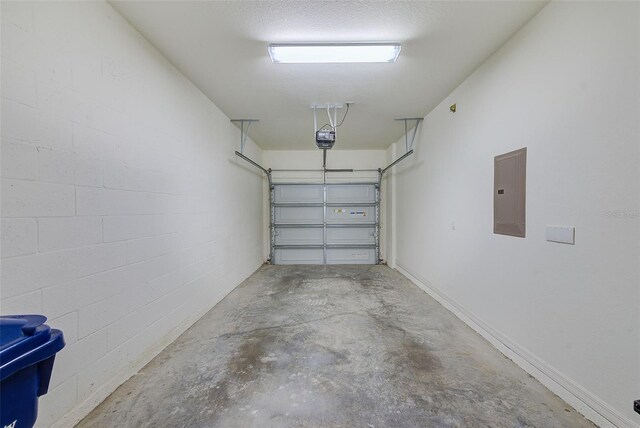 garage featuring concrete block wall, electric panel, and a garage door opener