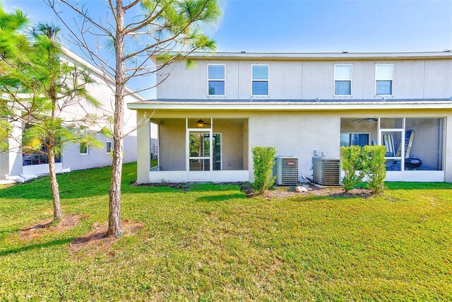 back of property featuring a sunroom, stucco siding, a lawn, and central air condition unit