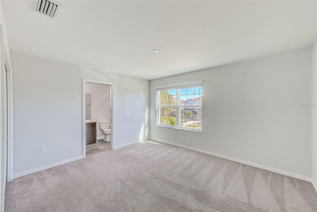 unfurnished bedroom featuring ensuite bath, baseboards, visible vents, and carpet flooring