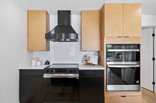 kitchen featuring decorative backsplash, light brown cabinetry, wall chimney exhaust hood, stainless steel appliances, and light hardwood / wood-style floors