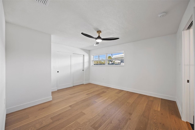 unfurnished bedroom featuring ceiling fan, a closet, a textured ceiling, and light hardwood / wood-style flooring