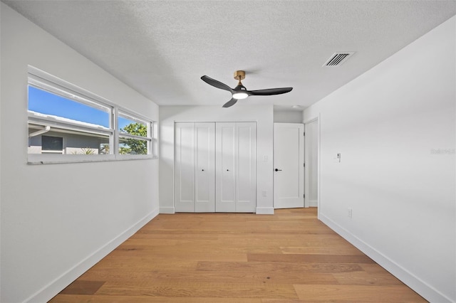 unfurnished bedroom featuring ceiling fan, light hardwood / wood-style floors, and a textured ceiling