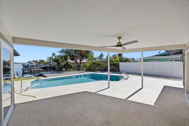 view of swimming pool featuring a patio, a water view, and ceiling fan