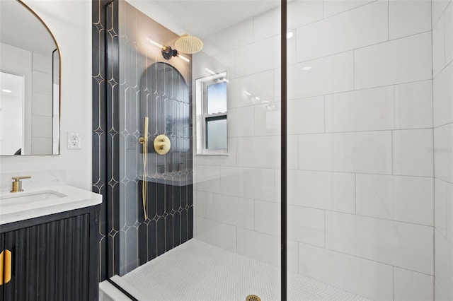 bathroom with a tile shower and vanity