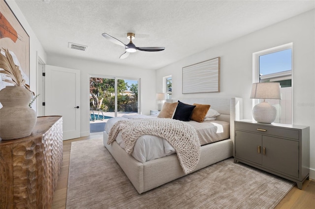 bedroom featuring access to exterior, a textured ceiling, light wood-type flooring, and ceiling fan