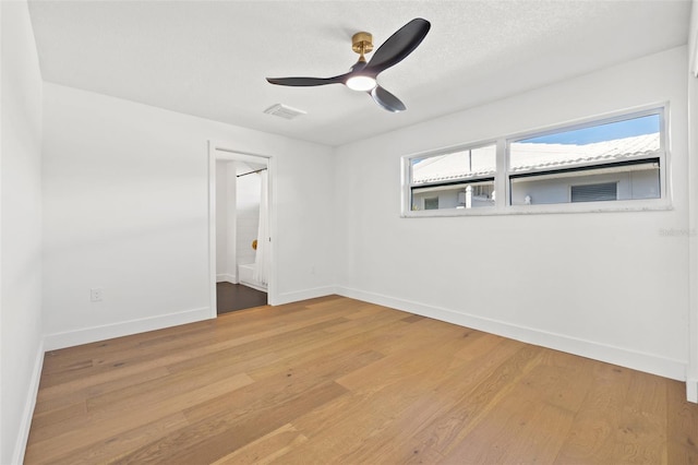 empty room with ceiling fan, hardwood / wood-style floors, and a textured ceiling