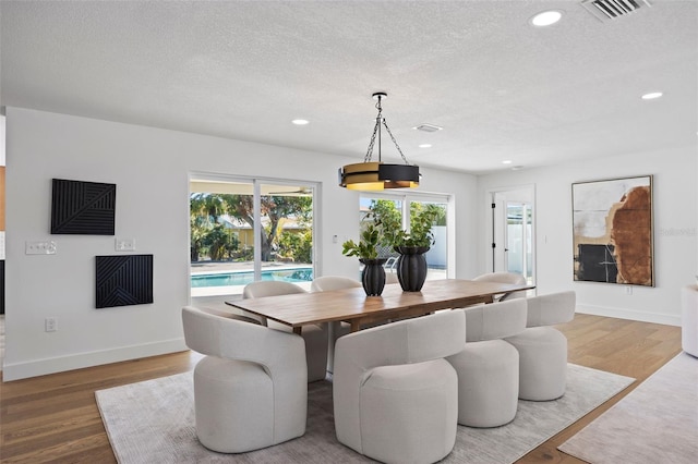 dining room featuring wood-type flooring and a textured ceiling