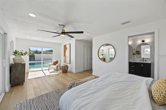 bedroom with access to exterior, ceiling fan, sink, light hardwood / wood-style flooring, and a textured ceiling