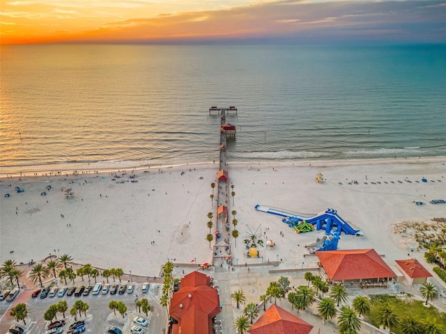 aerial view at dusk with a view of the beach and a water view