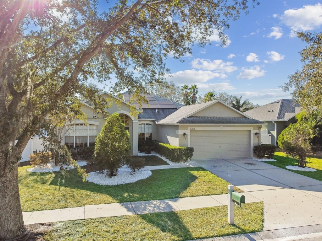 view of front of property featuring a front lawn, a garage, and solar panels