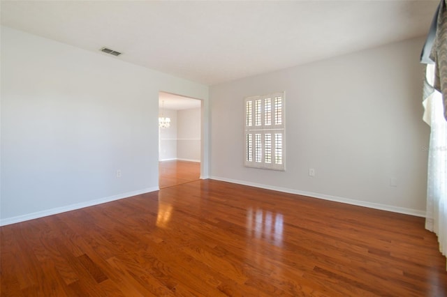 empty room featuring a notable chandelier and hardwood / wood-style flooring