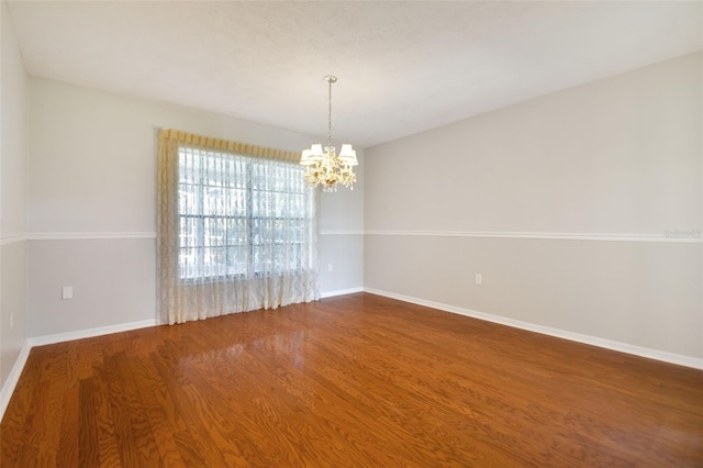 spare room featuring an inviting chandelier and hardwood / wood-style flooring