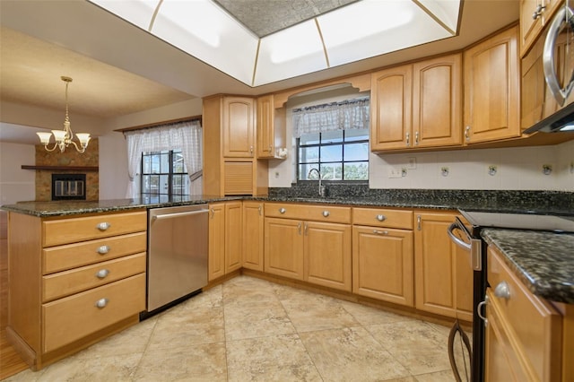 kitchen featuring sink, an inviting chandelier, dark stone counters, decorative light fixtures, and appliances with stainless steel finishes