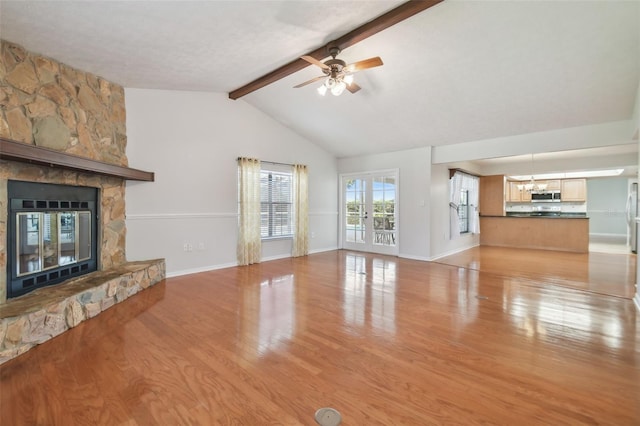 unfurnished living room with ceiling fan, french doors, lofted ceiling with beams, light hardwood / wood-style floors, and a fireplace