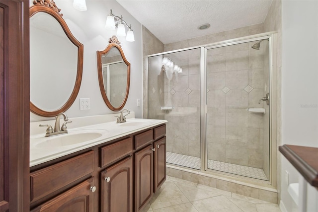 bathroom with a textured ceiling, vanity, tile patterned floors, and an enclosed shower