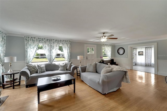 living room with ceiling fan, a healthy amount of sunlight, light wood-type flooring, and crown molding