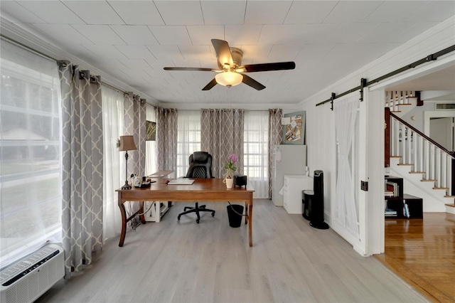 office featuring an AC wall unit, crown molding, ceiling fan, a barn door, and light hardwood / wood-style floors