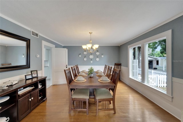 dining space featuring an inviting chandelier, crown molding, and light hardwood / wood-style flooring