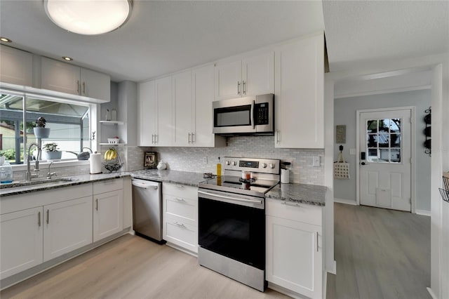 kitchen with sink, white cabinets, stainless steel appliances, and light wood-type flooring