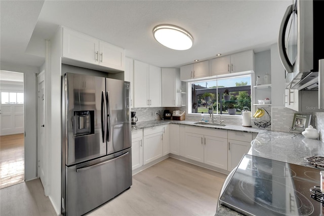 kitchen with tasteful backsplash, sink, white cabinets, and appliances with stainless steel finishes