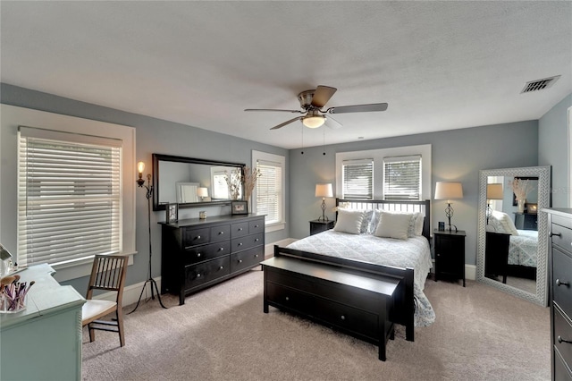 bedroom featuring a textured ceiling, light colored carpet, and ceiling fan