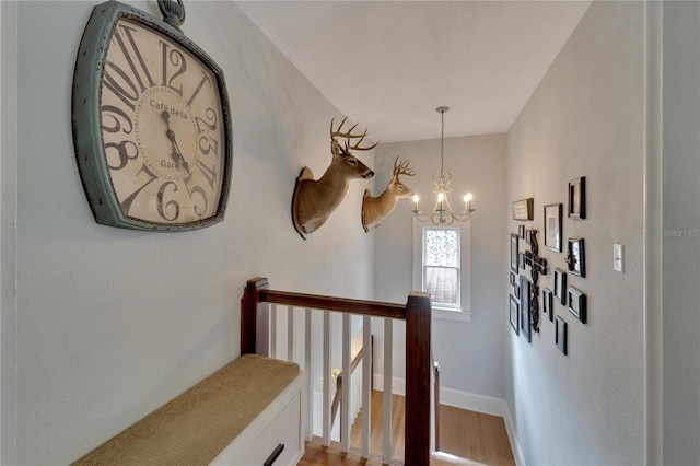 stairway with hardwood / wood-style flooring and a notable chandelier