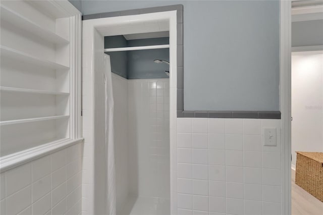 bathroom with built in features, tiled shower, and tile walls