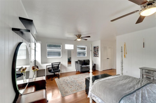 bedroom featuring hardwood / wood-style floors, ceiling fan, and wooden walls