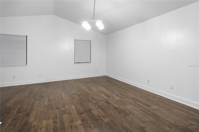 spare room featuring dark hardwood / wood-style floors, lofted ceiling, and an inviting chandelier