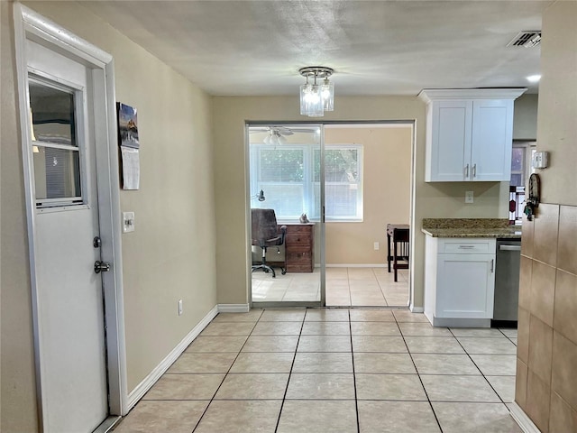 kitchen featuring dark stone countertops, white cabinetry, light tile patterned flooring, and stainless steel dishwasher