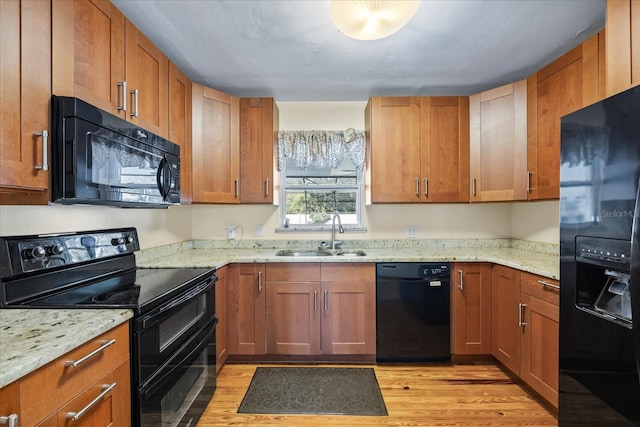 kitchen featuring light stone countertops, sink, light hardwood / wood-style floors, and black appliances