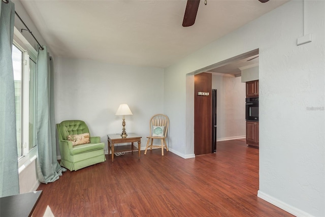 sitting room with ceiling fan and dark wood-type flooring