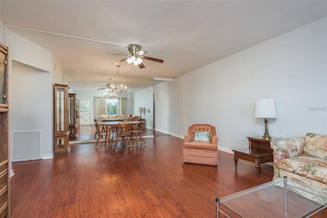 living room with ceiling fan with notable chandelier and dark hardwood / wood-style flooring