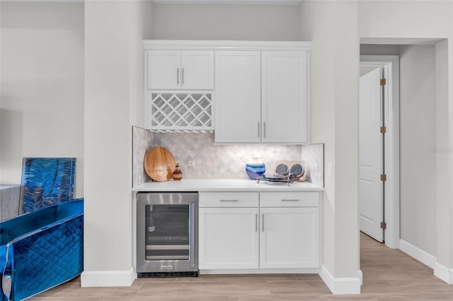 bar with light wood-type flooring, white cabinetry, wine cooler, and tasteful backsplash