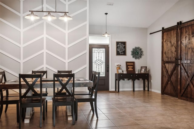 dining space with tile patterned floors, a barn door, and vaulted ceiling