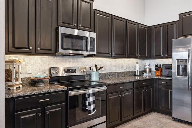 kitchen featuring appliances with stainless steel finishes, backsplash, light tile patterned floors, and dark stone countertops