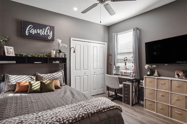 bedroom with a textured ceiling, a closet, light hardwood / wood-style flooring, and ceiling fan