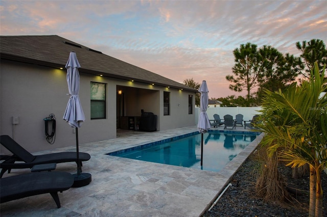 pool at dusk with a patio area