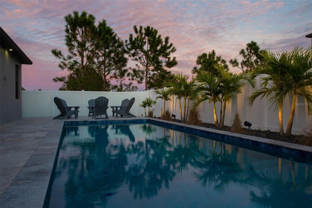 pool at dusk featuring a patio area