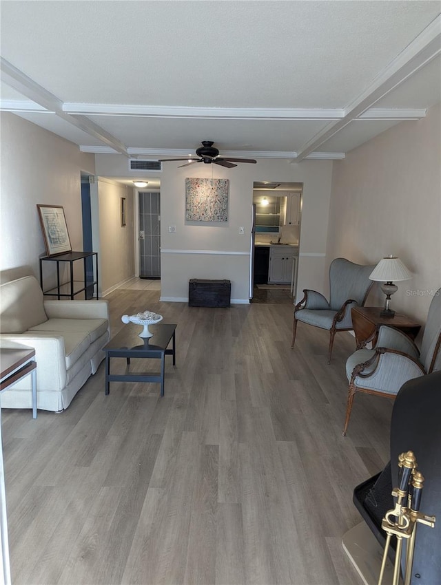 living room with hardwood / wood-style flooring, ceiling fan, and beam ceiling