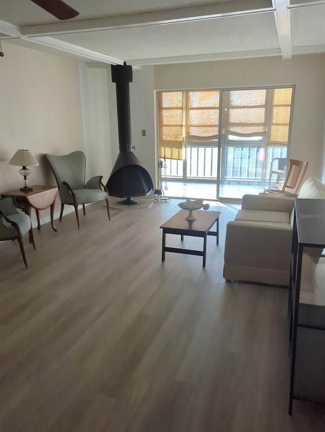 living room with hardwood / wood-style flooring, plenty of natural light, a wood stove, and beamed ceiling