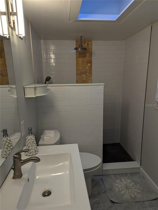 bathroom featuring sink, tile patterned floors, toilet, tiled shower, and tile walls