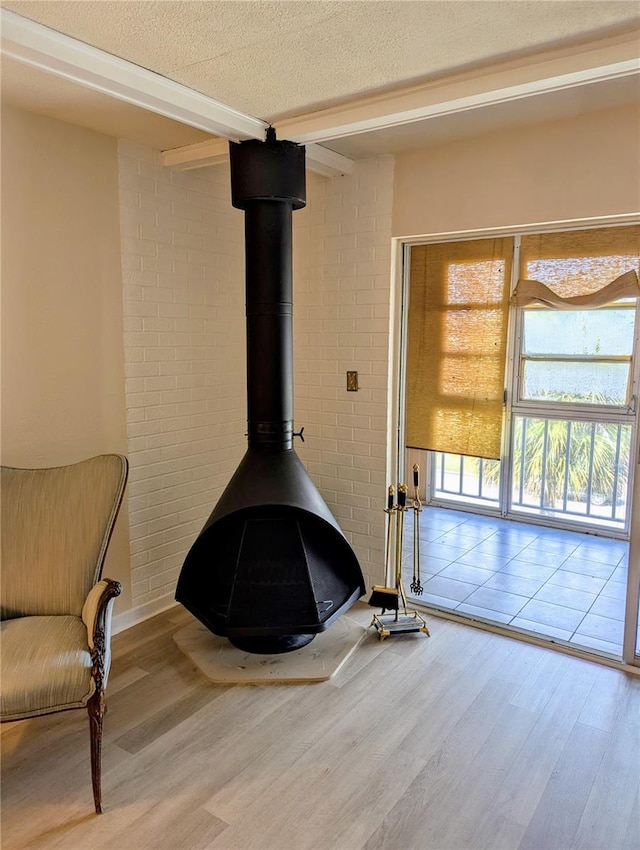 detailed view of wood finished floors, beamed ceiling, a wood stove, and a textured ceiling