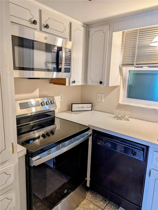 kitchen with stainless steel appliances, light countertops, and white cabinets